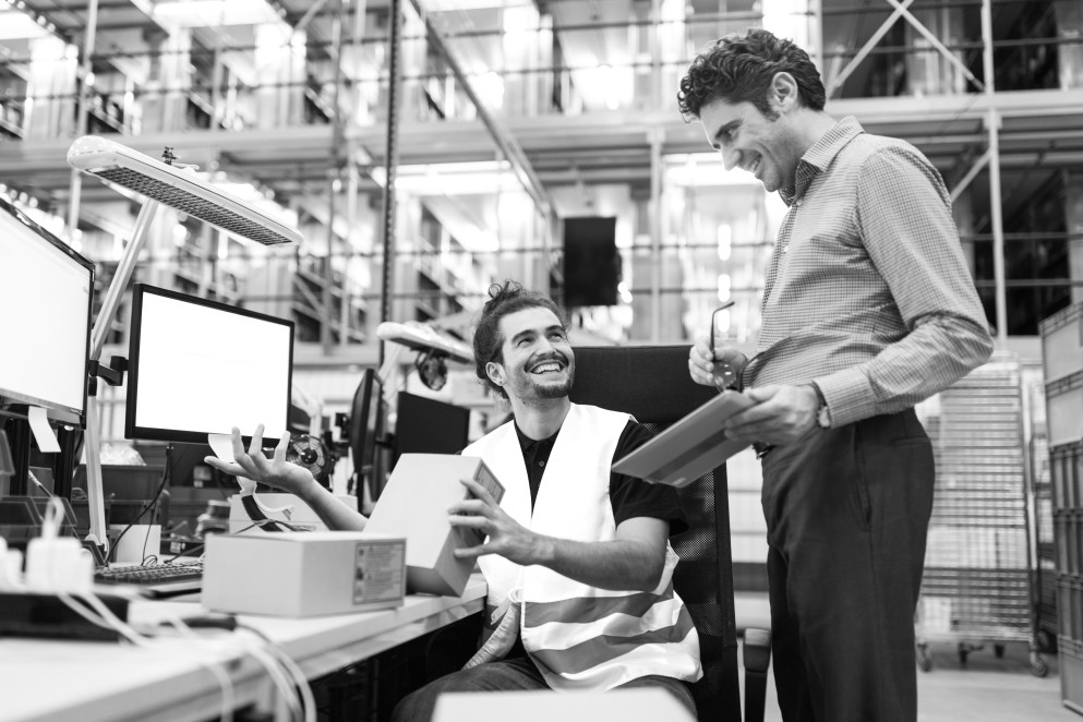 Two men in warehouse conversing over inventory
